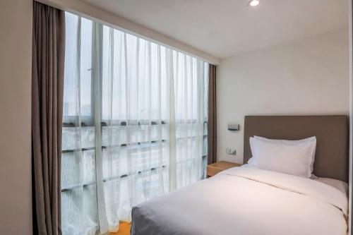 a bedroom with a bed and a large window at Holiday Inn Express Chengdu Xindu by IHG in Chengdu