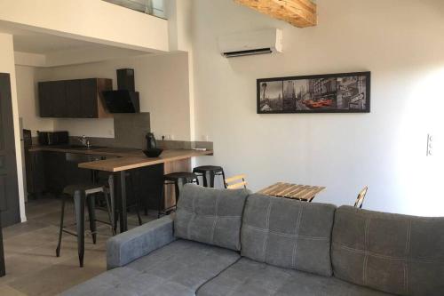 un salon avec un canapé et une table et une cuisine dans l'établissement Charmante maison à 5min de Marcoule, à Codolet