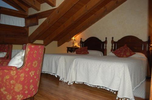 a bedroom with two beds and a red chair at HOTEL RURAL EL DENARIO in Garray