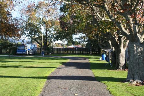 a walkway in a park with trees and grass at Levin TOP 10 Holiday Park in Levin