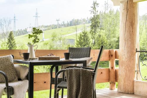 een patio met een tafel en stoelen op een balkon bij Domki w Białce WOODHOUSE- basen, sauna, jacuzzi in Białka Tatrzanska