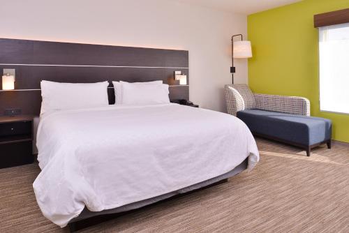 a hotel room with a large bed and a chair at Holiday Inn Express & Suites - Mall of America - MSP Airport by IHG in Bloomington