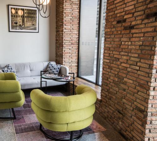 a living room with yellow chairs and a brick wall at Holiday Inn Telavi by IHG in Tʼelavi