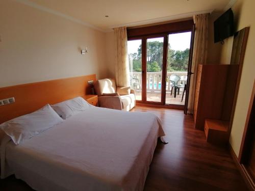 a bedroom with a white bed and a sliding glass door at Apartamentos Ay Sálvora in O Grove