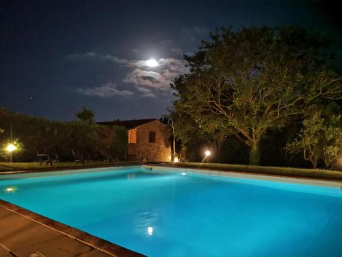 a swimming pool at night with the moon in the background at Agriturismo grecinella in Casole dʼElsa