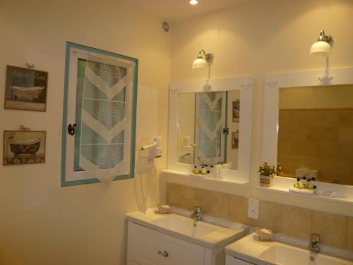 a bathroom with two sinks and two mirrors at Hotel Mistral in Mas blanc des Alpilles