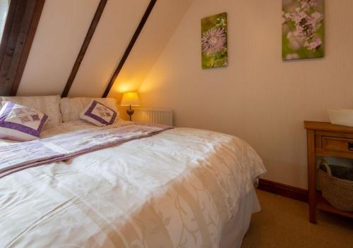 Demelza Cottage Apartment في بودمين: غرفة نوم بسرير وطاولة مع مصباح