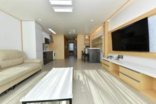 a living room with a couch and a flat screen tv at Sokcho Daemyung Heidi Pension in Sokcho