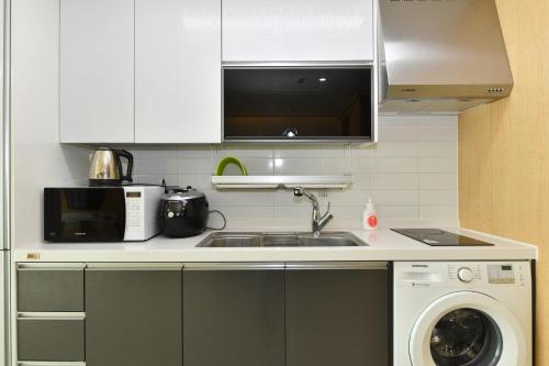 a kitchen with a sink and a washing machine at Sokcho Daemyung Heidi Pension in Sokcho