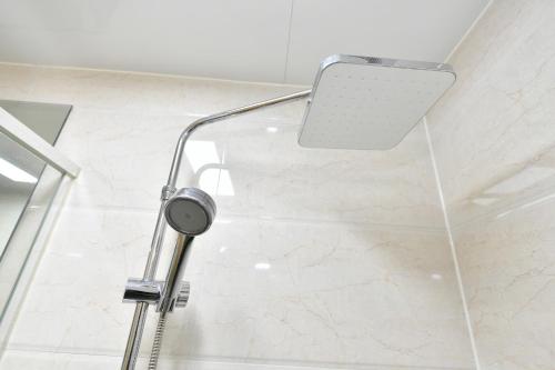 a shower in a bathroom with a shower head at Sokcho Daemyung Heidi Pension in Sokcho