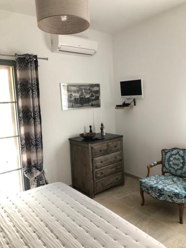 a bedroom with a bed and a chair and a television at Villa Capraghjese in Galeria
