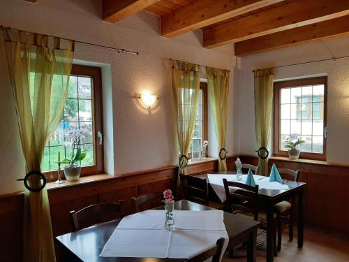 ein Restaurant mit 2 Tischen, Stühlen und Fenstern in der Unterkunft Linde Diersburg in Hohberg