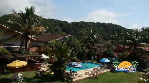 a resort with a swimming pool and palm trees at Pousada Dolce Vita in Itanhaém