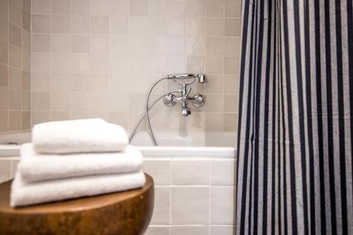 a bathroom with a tub and a pile of towels at Hôtel Le Sud in Juan-les-Pins