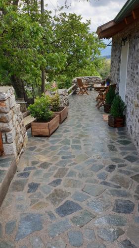 a patio with benches and potted plants next to a building at The House in the Cobbled Road in Karpenision