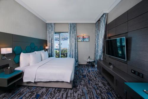 a hotel room with a bed and a flat screen tv at Edge Creekside Hotel in Dubai