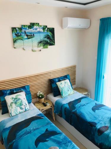 two beds in a room with blue sheets and dolphin paintings at Relax Apartment in Perea
