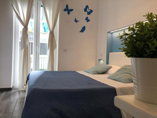 ein Schlafzimmer mit einem Bett mit blauer Bettwäsche und einer Pflanze in der Unterkunft CIVICO 29 in Pompei
