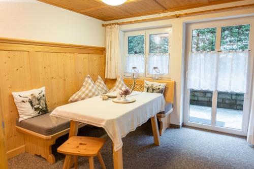 a room with a table and a chair and windows at Das Tannacker - Ferienwohnungen Hartmann in Fischen