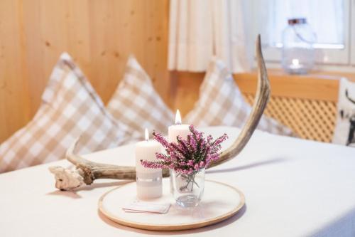 a table with two candles and a centerpiece with antlers at Das Tannacker - Ferienwohnungen Hartmann in Fischen