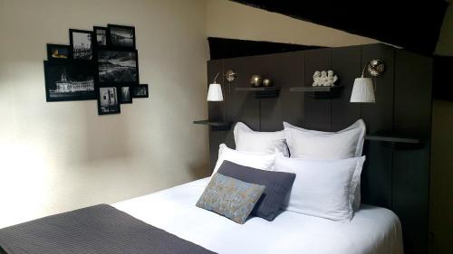 une chambre avec un lit avec des draps blancs et des oreillers dans l'établissement Coeur de Saint Pierre, à Bordeaux