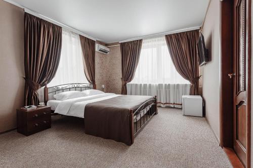 ein Schlafzimmer mit einem Bett und zwei großen Fenstern in der Unterkunft Bulgary House in Kryschaniwka