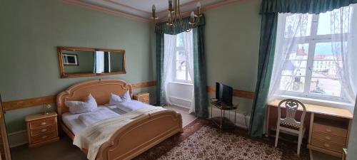 a bedroom with a bed and a desk and windows at Hotel zum Schwan in Bad Karlshafen