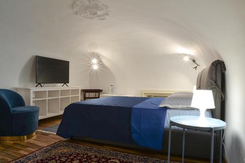 sypialnia z niebieskim łóżkiem i telewizorem z płaskim ekranem w obiekcie Filomena Suite Luxury Apartment w Katanii