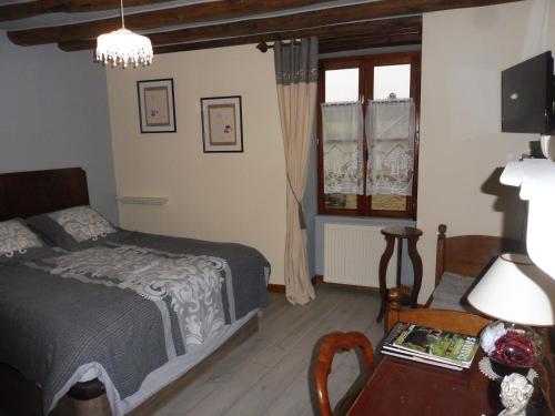 a bedroom with a bed and a table at Chambre d'hôtes des 3 ifs in Vernot