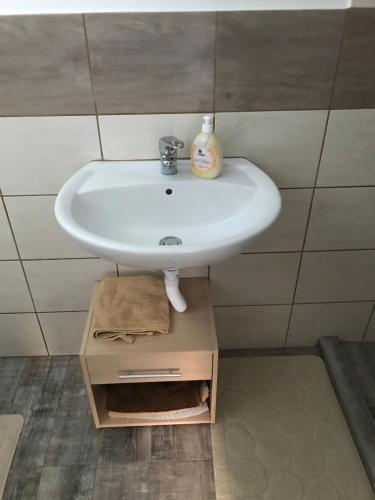 un lavabo en un baño con una caja debajo en Nyugalom Pihenő, en Kisújszállás