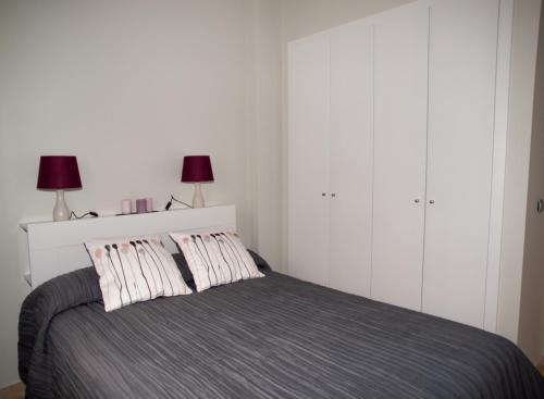 a bedroom with a bed with two pillows and two lamps at La Casa del Arte in Cádiz