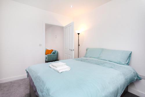 a bedroom with a blue bed with towels on it at Smart Apartment Close2City in Leicester