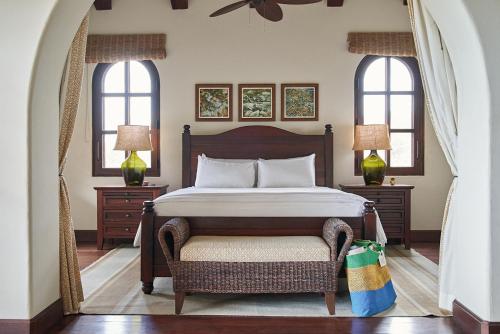 a bedroom with a bed with a chair and two windows at Rancho Santana in El Limón