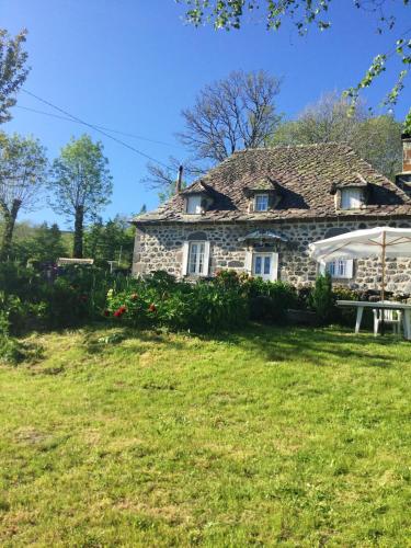 une ancienne maison en pierre avec un parasol dans une cour dans l'établissement Maison confortable avec vue sur la montagne à Le Fau, à Le Fau