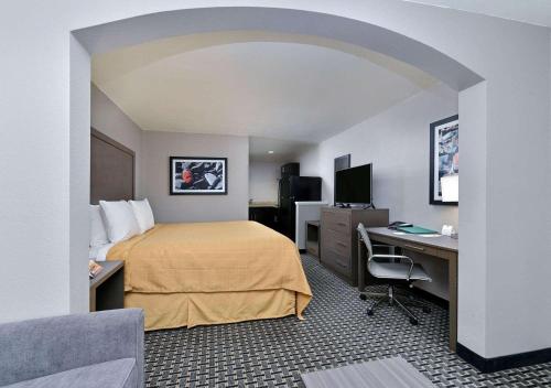 a hotel room with a bed and a desk with a computer at Scottish Inn & Suites Cotulla, TX in Cotulla