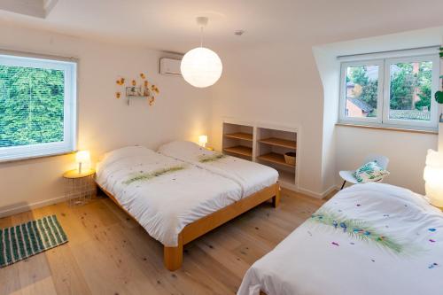 a bedroom with two beds and two windows at Vakantiehuis Elisa in Alken