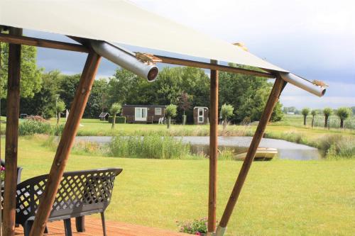 a gazebo with a bench in a park at Safaritenten Schotererf in Kuinre