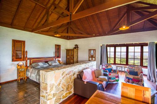 a bedroom with a bed and chairs in a room at Magnificat Cottage in Cunha