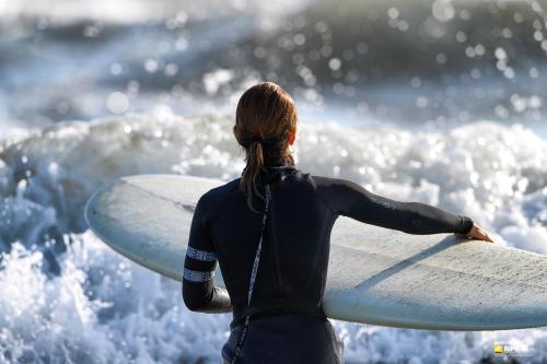 a woman in a wet suit holding a surfboard at Hotel Residence Villa Jolanda in Lido di Camaiore