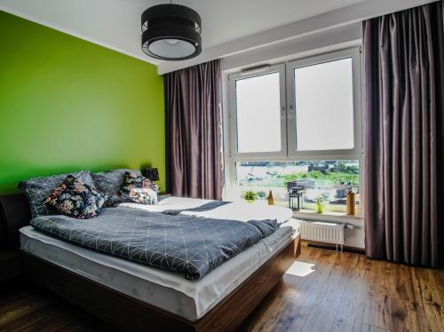 - une chambre avec un lit aux murs verts et une fenêtre dans l'établissement SUNRISE HOME w sercu Gdańska, à Gdańsk