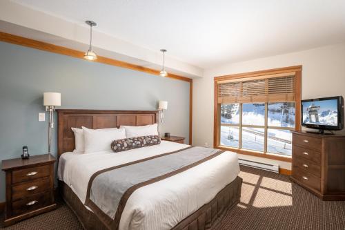 1 dormitorio con 1 cama, TV y ventana en Legends, en Whistler