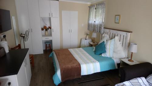 a bedroom with a bed with blue and white pillows at Welterusten Guesthouse in Strand