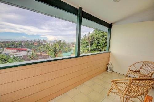 a balcony with two chairs and a large window at King Solomon Hotel in Honiara