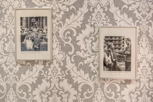 tres fotografías enmarcadas en una pared con papel pintado en Marta Inn en Roma