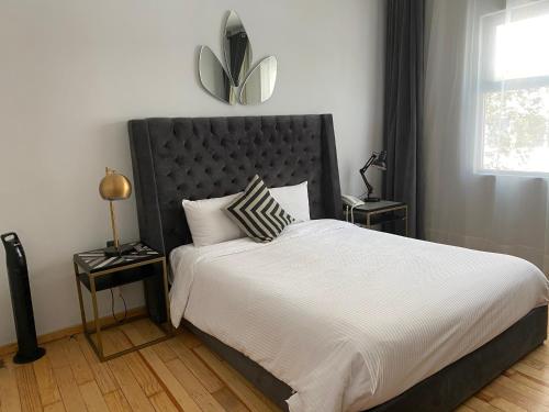 a bedroom with a large bed with a black headboard at Suites Alcazar in Mexico City
