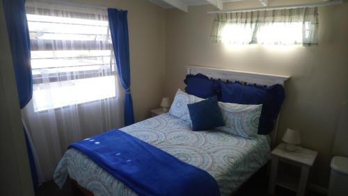 a bedroom with a bed with blue sheets and a window at Welterusten Guesthouse in Strand