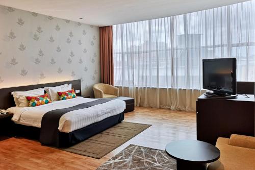 a bedroom with a bed and a tv and a couch at The LimeTree Hotel, Kuching in Kuching