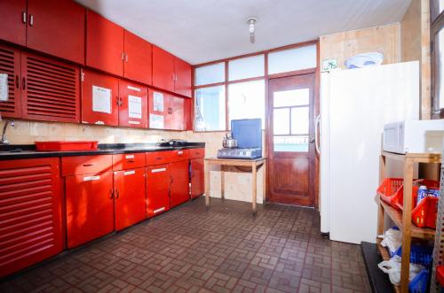 a kitchen with red cabinets and a white refrigerator at Arequipay Hostel in Arequipa