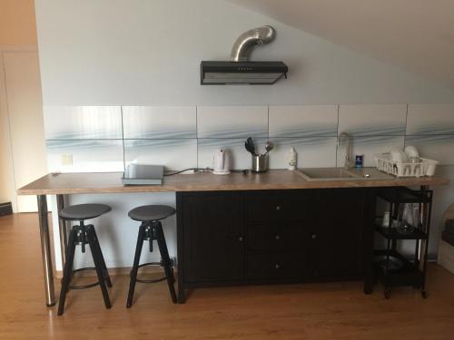 eine Küche mit einer Theke, einer Spüle und Hockern in der Unterkunft Perlos apartamentai 13 butas in Birštonas