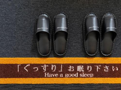 two pairs of shoes on top of a yellow stripe at Super Hotel Beppu Ekimae in Beppu